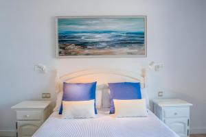 a bedroom with a bed with blue and white pillows at Bungalow 3 - Caleta Campos in Arrieta