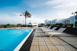 a row of white lounge chairs next to a swimming pool at Bungalow 3 - Caleta Campos in Arrieta