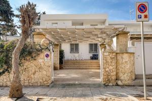 a white house with a stone wall and a gate at Appartamento Luce sulla spiaggia in Torre San Giovanni Ugento