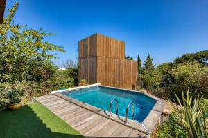 a swimming pool in a garden with a wooden building at Maison Greenkub in Générac