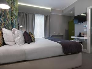 a bedroom with a large white bed with pillows at Anjoy&Bleev Rooms in Rho