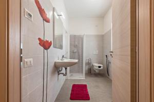a bathroom with a sink and a toilet with a red rug at Nonno Bigi Papavero in Tremosine Sul Garda