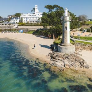 a man walking on the beach next to a lighthouse at Studio vue mer - 50m de la plage in Bénodet