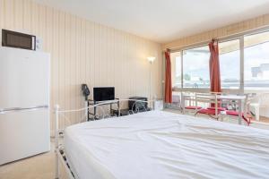 a bedroom with a bed and a table and a refrigerator at Studio vue mer - 50m de la plage in Bénodet