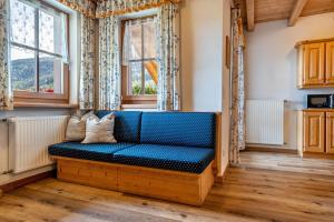 a blue couch in a room with windows at Kranebitterhof Apt Enzian in Valdaora +25 photos