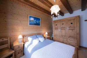 a bedroom with a white bed and wooden walls at Gîte La Clé Des Champs in Manigod