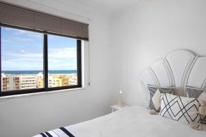 a bedroom with a white bed and a large window at Lindo T2 com vista mar in Quarteira