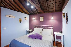 a bedroom with a bed with purple walls and purple pillows at La Chirlaca in Tijarafe