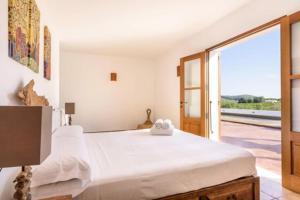 a bedroom with a large white bed and a sliding glass door at Villa Dalt S Era in Santa Gertrudis de Fruitera +22 photos