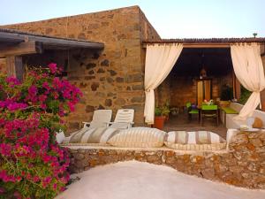 a patio with white chairs and a table and flowers at Antico Dammuso Invernale in Pantelleria