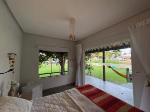 a bedroom with a bed and a large window at Rancho Capilé Suítes à Beira Mar in Japaratinga