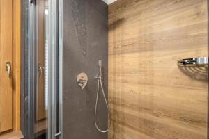 a shower in a bathroom with a wooden wall at Villa Elma - Livigno in Livigno