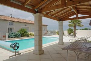 a patio with a pool and a wooden pergola at Chambre d'hôtes La Champagne in Sémussac