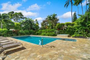 a swimming pool with chairs and palm trees at Ocean Bluff Gem in Princeville Beach Access Pool in Princeville