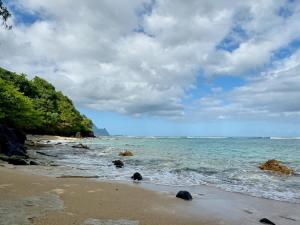 a beach with rocks and the ocean on a cloudy day at Ocean Bluff Gem in Princeville Beach Access Pool in Princeville