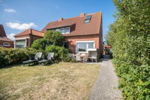 a house with two chairs and a table in the yard at Seehaus Juist in Juist