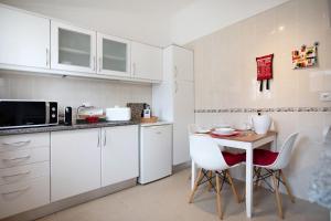 a kitchen with white cabinets and a table and chairs at Páteo da Várzea 5 in Colares