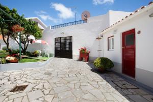 a white house with a red door and a patio at Páteo da Várzea 5 in Colares