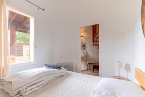 a white bedroom with a bed and a window at Maisonnette Biscarosse in Biscarrosse