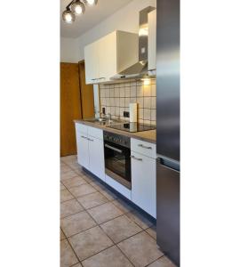 a kitchen with white cabinets and a stove at Ferienwohnung Zum Plauderbaum in Balve