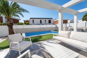a patio with white furniture and a palm tree at Casa Bos Palm Tree Villa with Pool in Gran Alacant