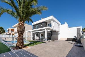 a palm tree in front of a white house at Casa Bos Palm Tree Villa with Pool in Gran Alacant