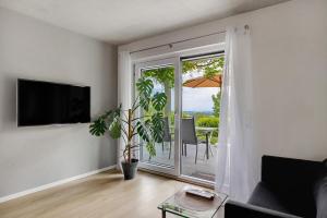 a living room with a tv and a balcony with an umbrella at Ferienwohnung Frieda in Frickingen