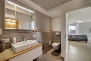 a bathroom with a sink and a toilet and a bed at Ferienwohnung Frieda in Frickingen +18 photos