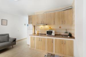 a kitchen with wooden cabinets and a microwave at Apartamento Danoe 3 in Mogán +12 photos