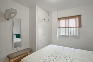 a white bedroom with a bed and a window at Apartamento Danoe 3 in Mogán
