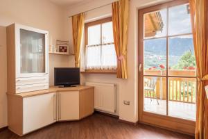 a living room with a television and a large window at Tischlerhof - Typ B mit Terrasse in Tirolo