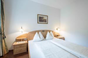 a bedroom with a white bed with two pillows at Tischlerhof - Typ B mit Terrasse in Tirolo