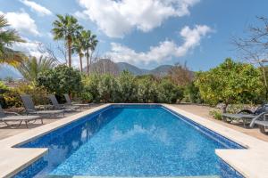 a pool with chairs and trees and mountains in the background at Finca Ca'n Vaqueta in Sóller