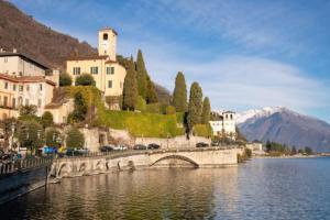 a bridge over a body of water with buildings and a mountain at Gravedona Lake Como in Consiglio di Rumo