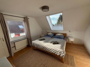 a small bedroom with a bed and two windows at Landhausappartment in Bermatingen