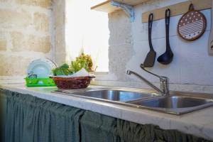 a kitchen counter with a sink and utensils on the wall at La Casa di Marta in Faccia di Trippa +17 photos
