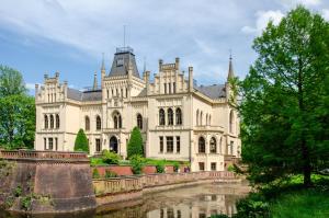 a large castle with a river in front of it at Haus Scheve in Rhauderfehn