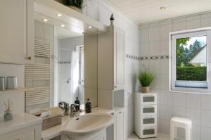 a white bathroom with a sink and a mirror at Haus Scheve in Rhauderfehn +22 photos