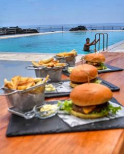 a table with hamburgers and french fries and a pool at Pico Boutique House in Lajes do Pico