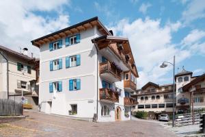 a white building with wooden balconies on a street at Piaz de Vich in Vigo di Fassa