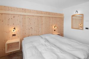 a bedroom with a white bed and a wooden wall at Piaz de Vich in Vigo di Fassa