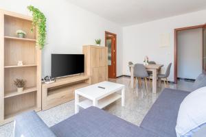 a living room with a tv and a couch and a table at Can Lopits in L'Escala