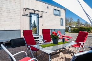 eine Terrasse mit Tisch und Stühlen und ein Gebäude in der Unterkunft Tiny House Ingo John 'Shadow' in Sandstedt