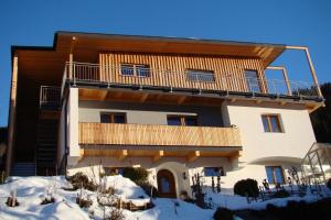 a house with a balcony on top of it in the snow at Ferienwohnung Serlesblick in Mieders