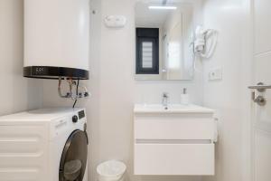 a white bathroom with a washing machine and a sink at Apartamento The Stairs 2 11 in Tarifa