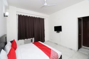 a bedroom with a bed with red pillows and a television at Hotel O The Primero Near Leisure Valley Park in Gurgaon
