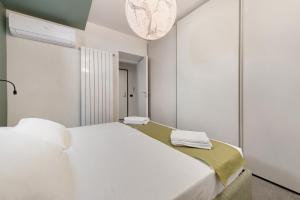 a bedroom with a large white bed and a chandelier at Gemhouse Smeraldo garda lake in Gargnano