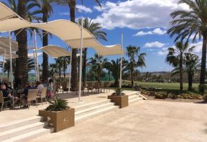a group of people sitting at tables under palm trees at Los Almendros in Vera