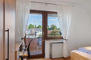 a bedroom with a door with curtains and a balcony at Ferienwohnung Markelfingen in Radolfzell am Bodensee