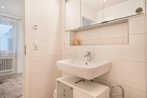 a white bathroom with a sink and a mirror at Ferienwohnung Gartenstraße in Lindau-Bodolz +14 photos